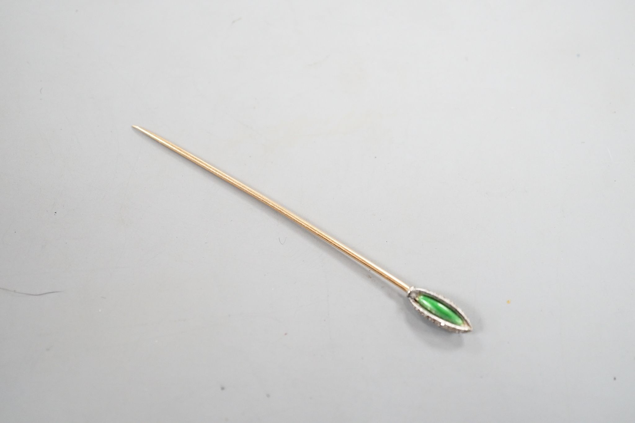 An early 20th century yellow metal stick pin, with rose cut diamond and green enamel set terminal, 76mm, gross weight 2.3 grams.